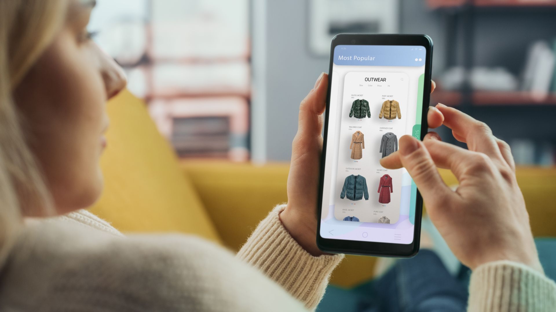 Person using a smartphone shopping app, browsing clothing items on screen and tapping a product.