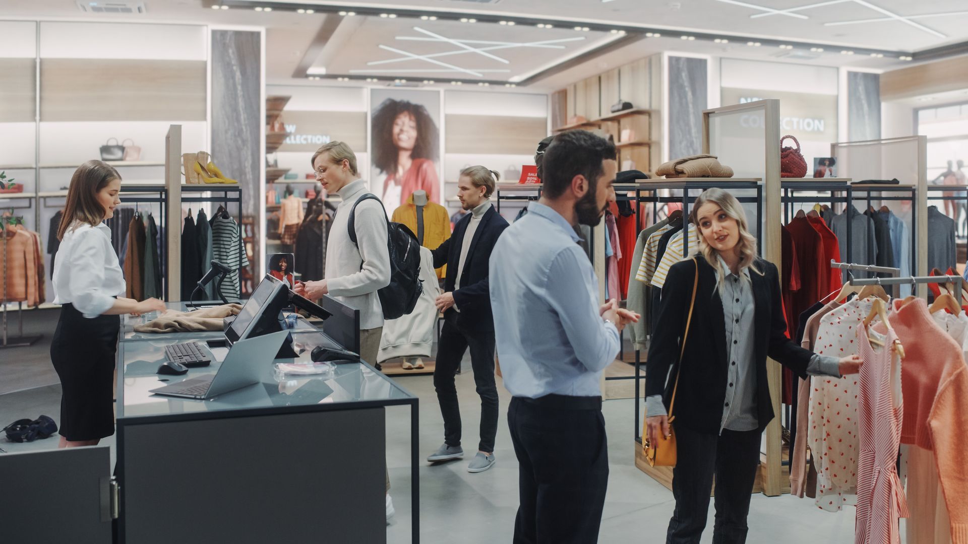 People browsing clothes in a bright fashion store with racks of colorful garments and mannequins