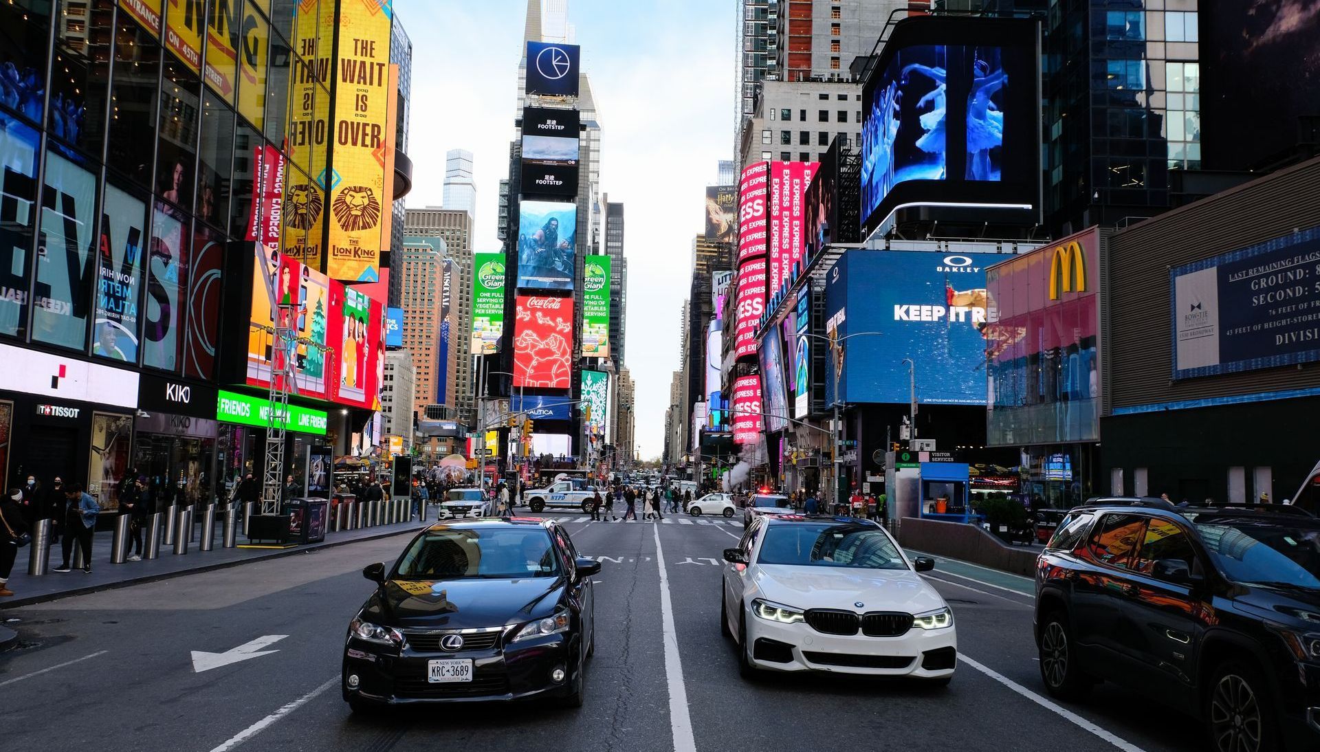 Traffic on a busy Times Square street with bright billboards and cars under towering buildings