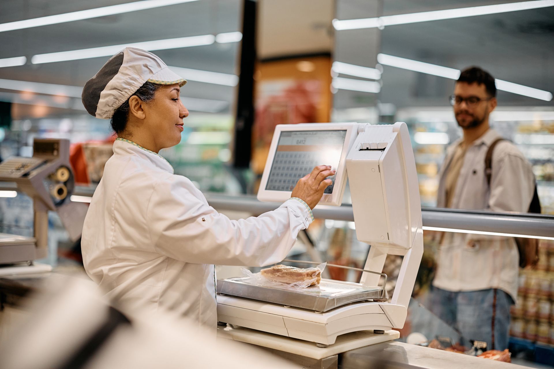 Bakery worker using a touchscreen cash register while serving a customer at the counter