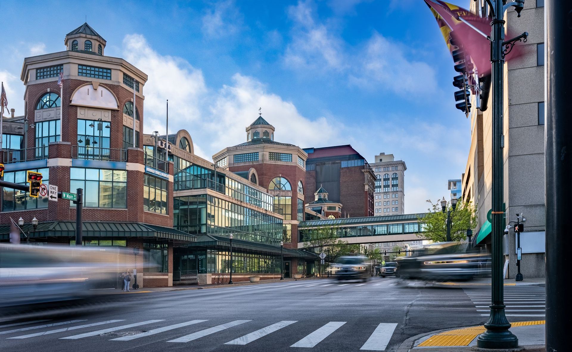 Historic brick buildings and glass skybridge over a quiet city street on a clear day