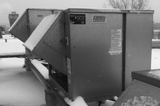 Une photo en noir et blanc d'une grande boîte en métal recouverte de neige.