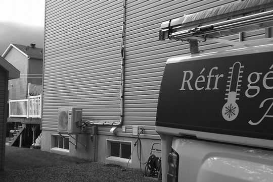 Une photo en noir et blanc d'un camion frigorifique garé devant une maison
