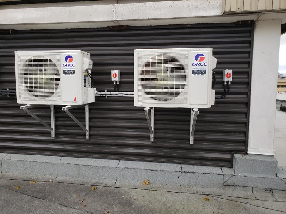 Deux climatiseurs sont montés sur le côté d'un bâtiment.