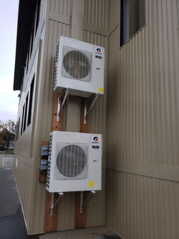 Deux climatiseurs sont montés sur le côté d'un bâtiment.