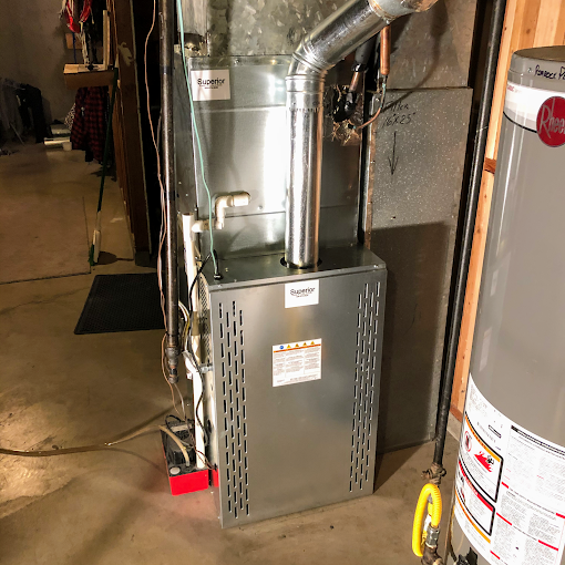 A water heater is sitting next to a heating system in a basement.