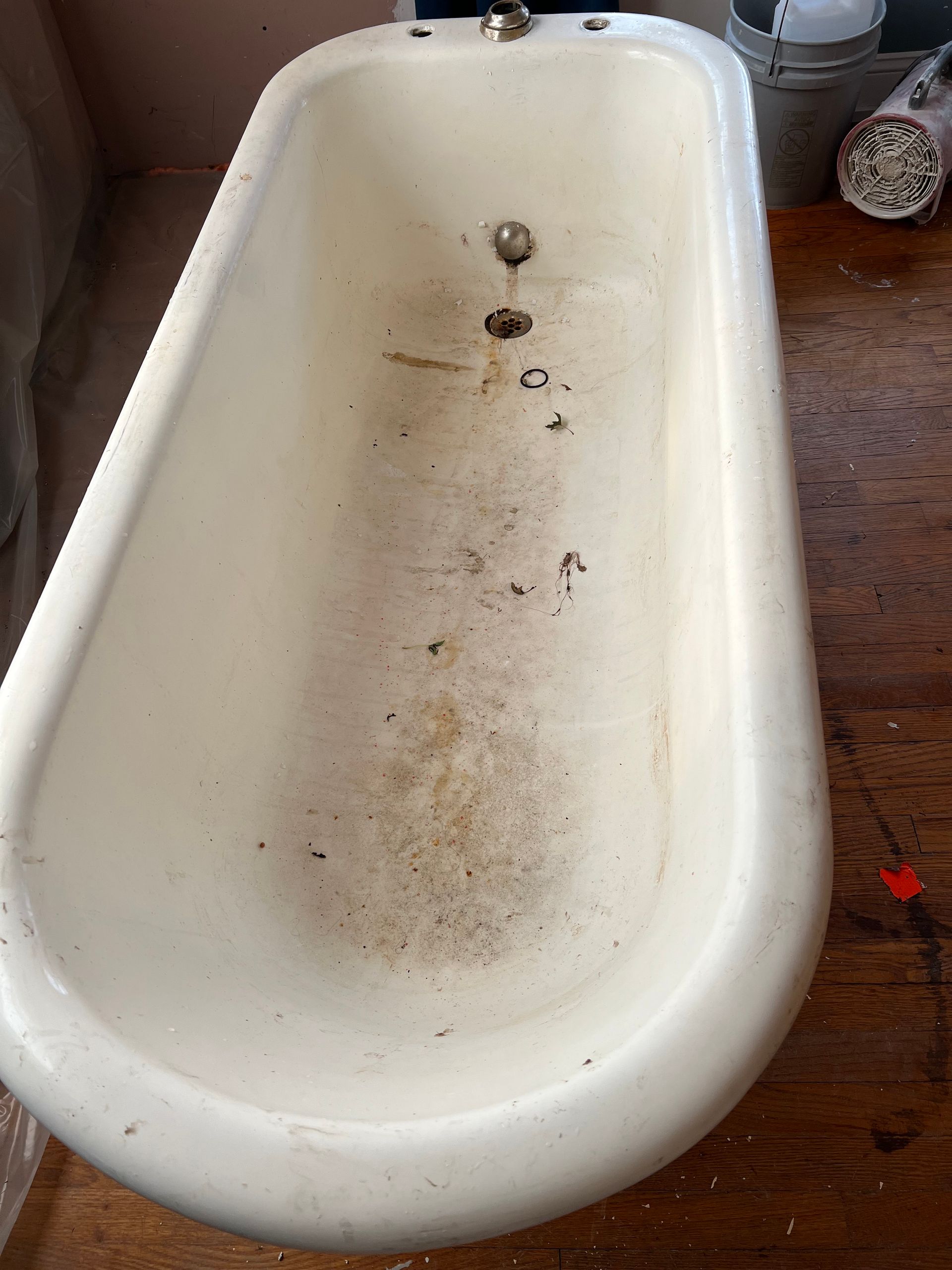 A white bathtub is sitting on a wooden floor.