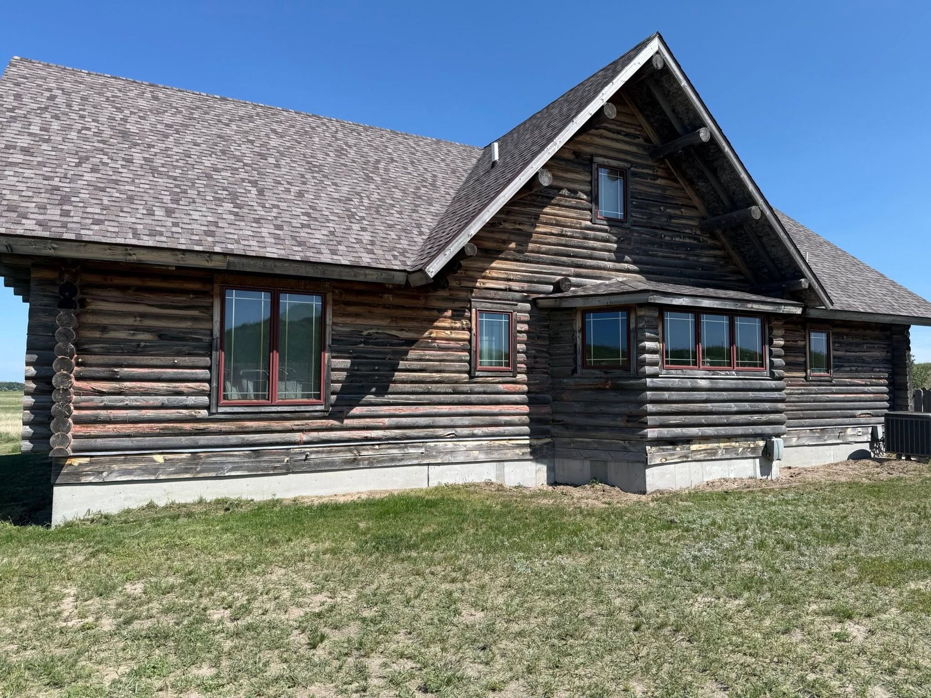 Rustic log cabin with a steep roof and small porch under a clear blue sky