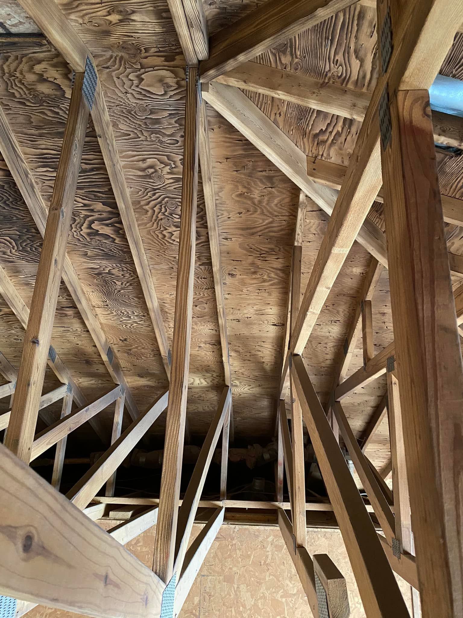 Exposed wooden roof trusses and beams inside an unfinished attic or ceiling space