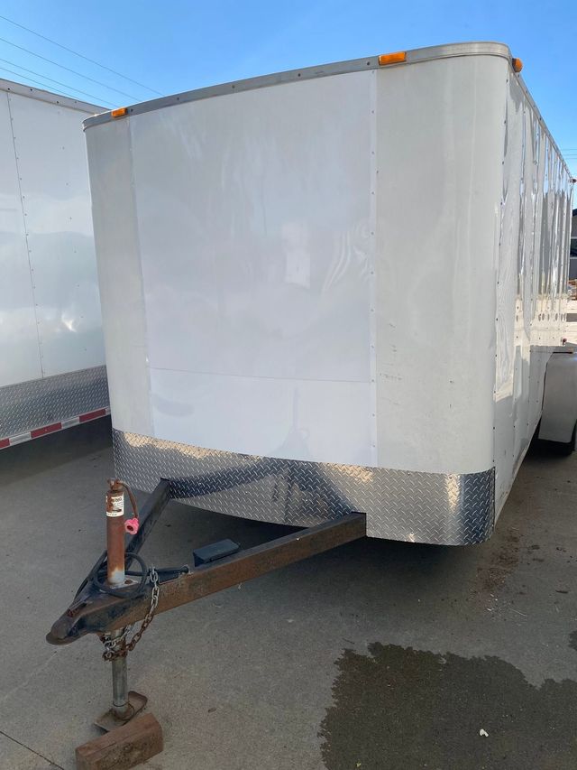 White enclosed cargo trailer parked outdoors, front hitch visible on pavement.