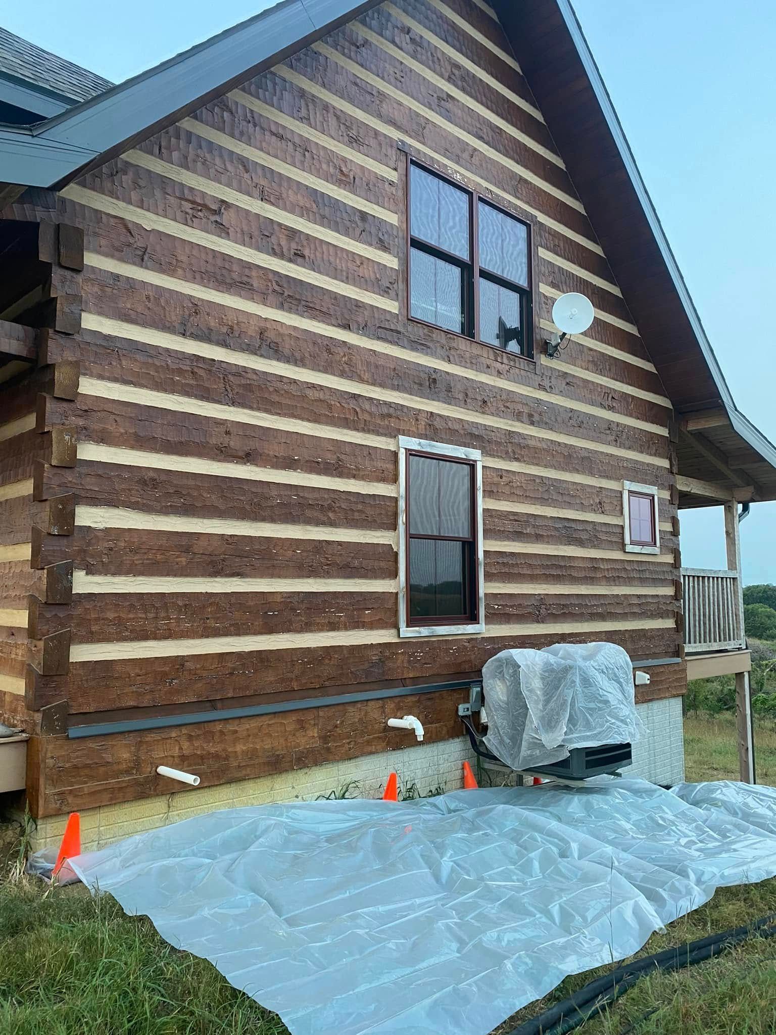 House exterior under construction with striped wood siding, plastic sheeting, and a covered object beside it