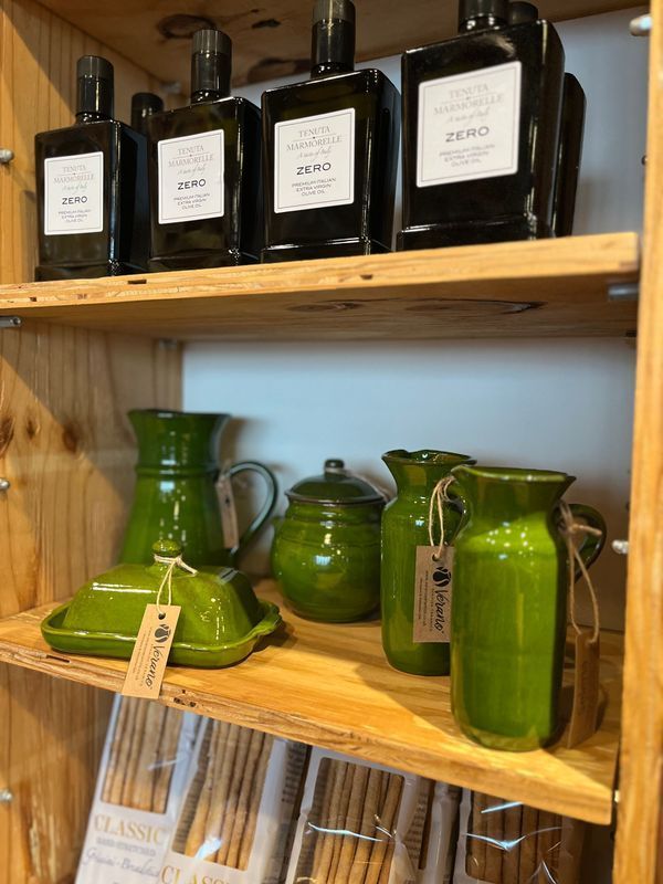 Wooden shelf with black and green glass bottles and pitchers on display