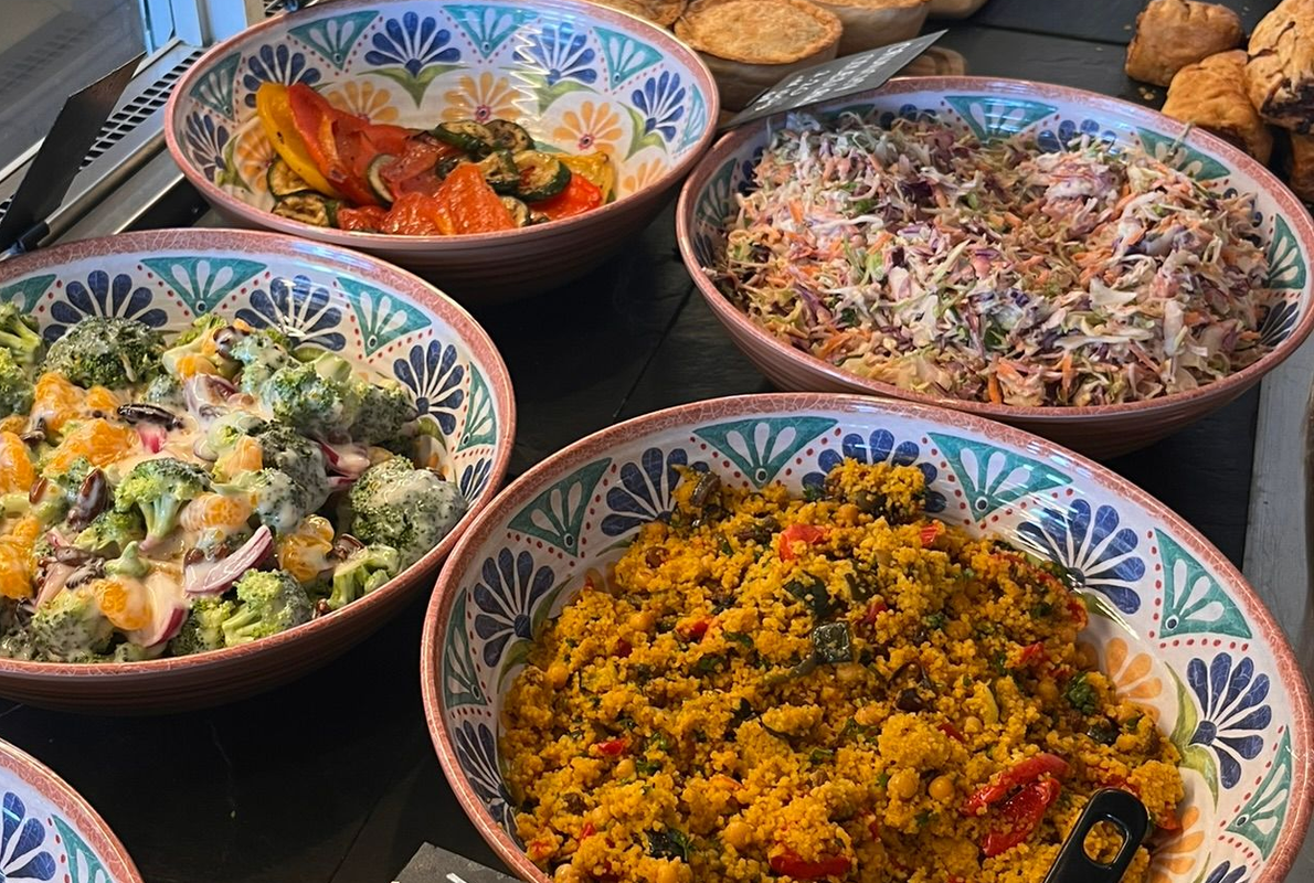 Four bowls of colorful grain and vegetable salads on a dark table