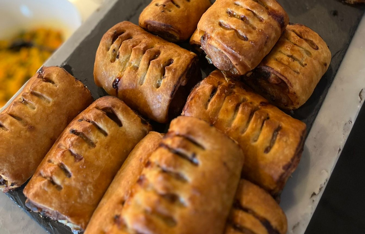 Golden-brown pastries arranged on a baking tray, with slits on top and a glossy baked finish.