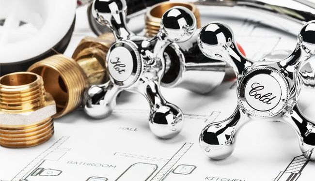 Chrome and brass plumbing fixtures over a bathroom blueprint