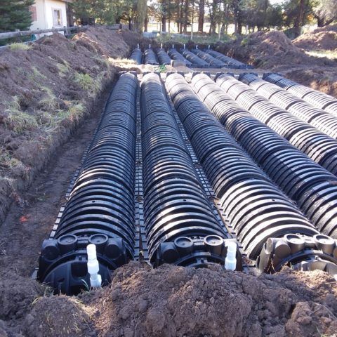 Rows of black drainage pipes laid in a trench at a construction site