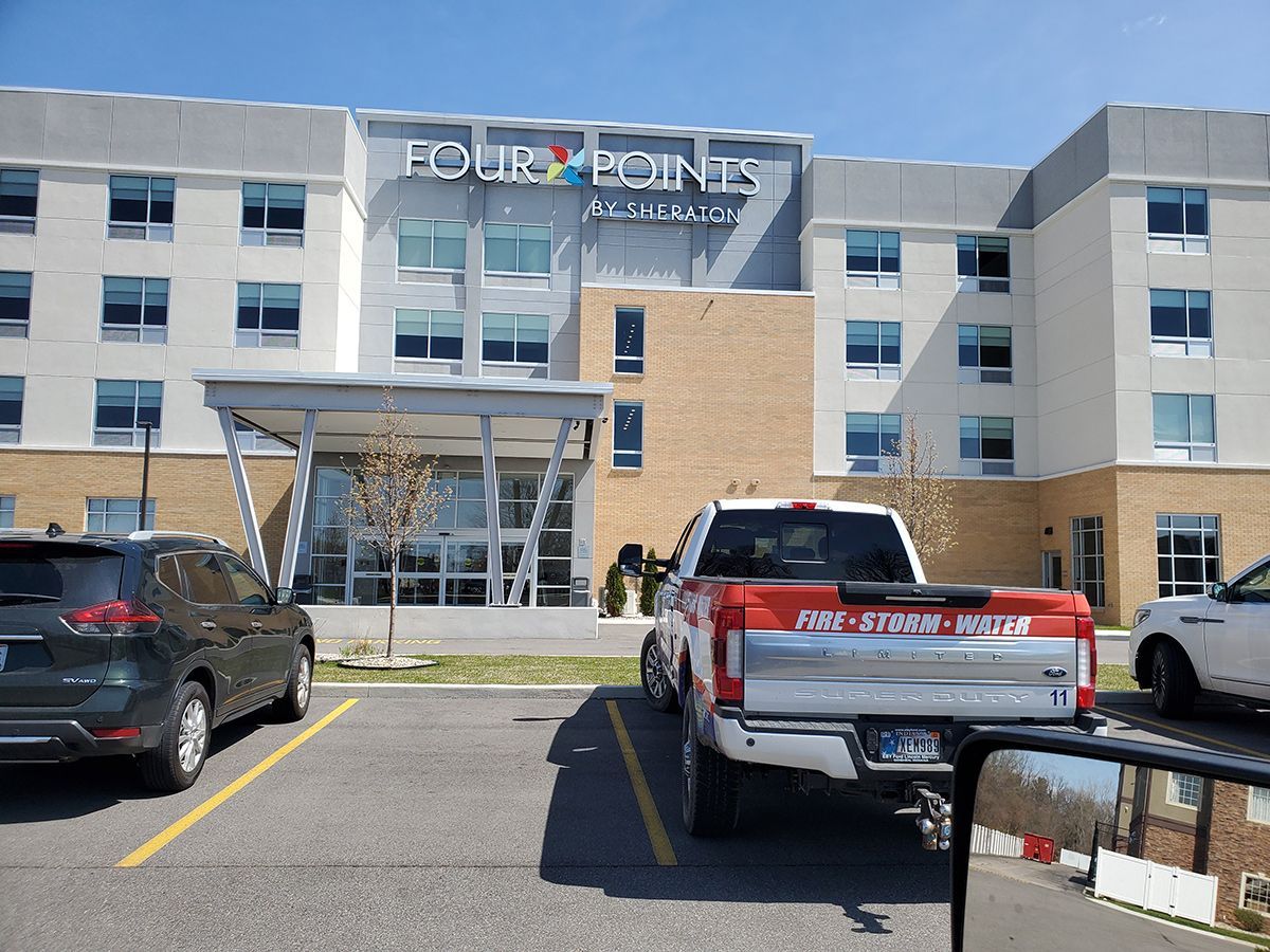 Front entrance of a modern hotel with parked cars in the lot