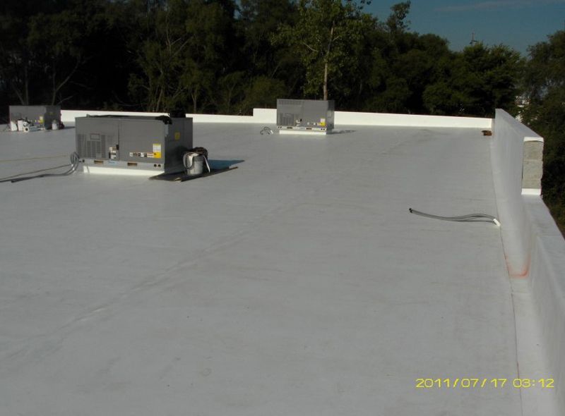 Flat white rooftop with two HVAC units and trees in the background.