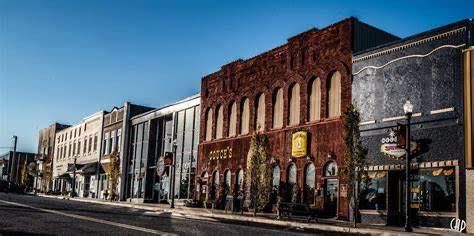 Small-town main street with historic storefronts and brick buildings under a clear blue sky