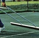 a person is using a broom to clean a tennis court