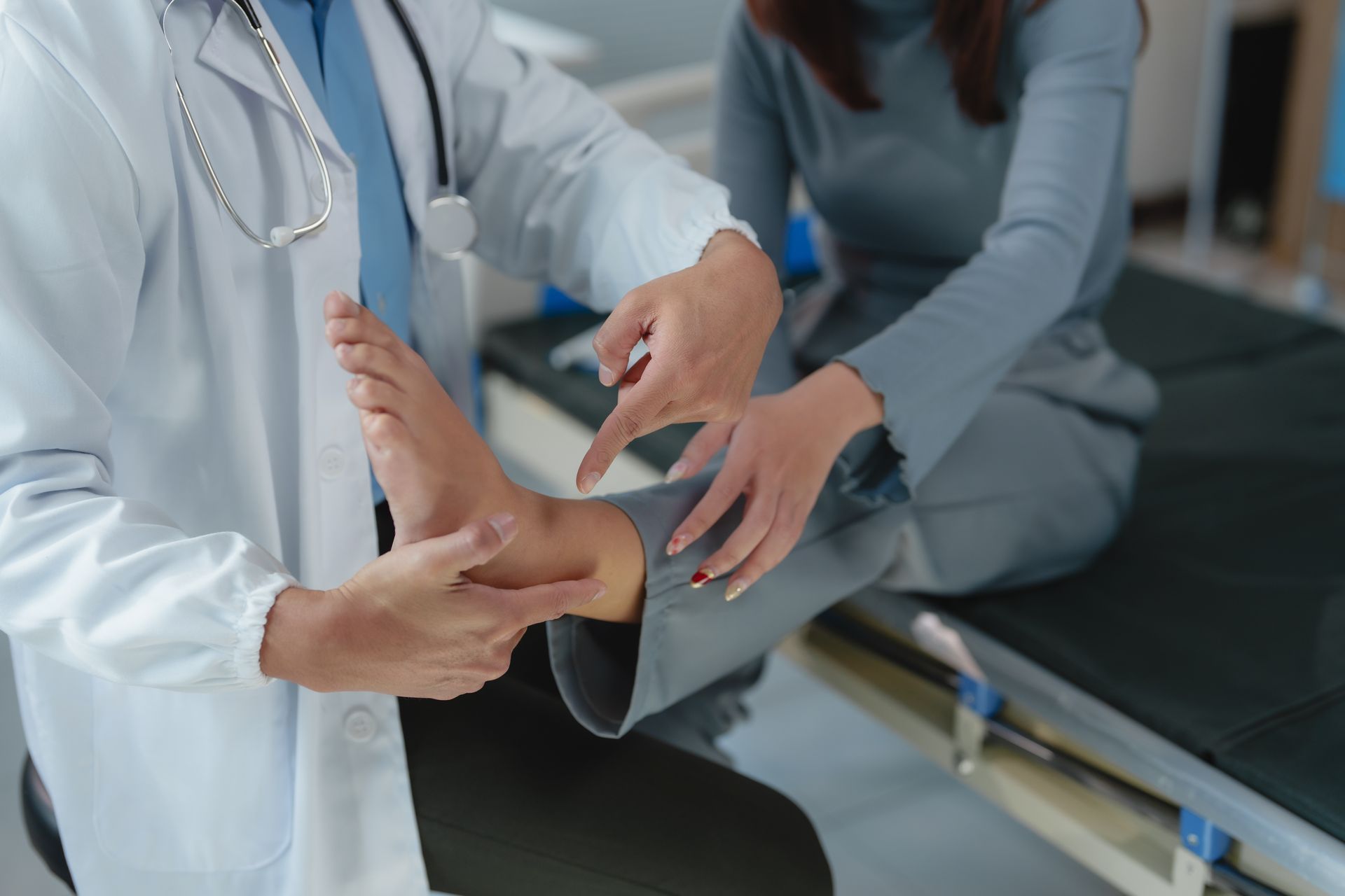 Doctor examining a patient's ankle in an examination room.