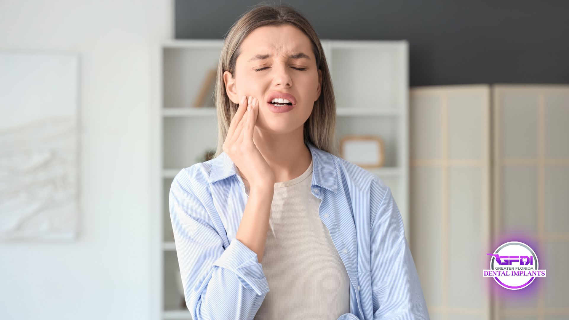 Woman with hand on cheek, showing discomfort, inside a room.