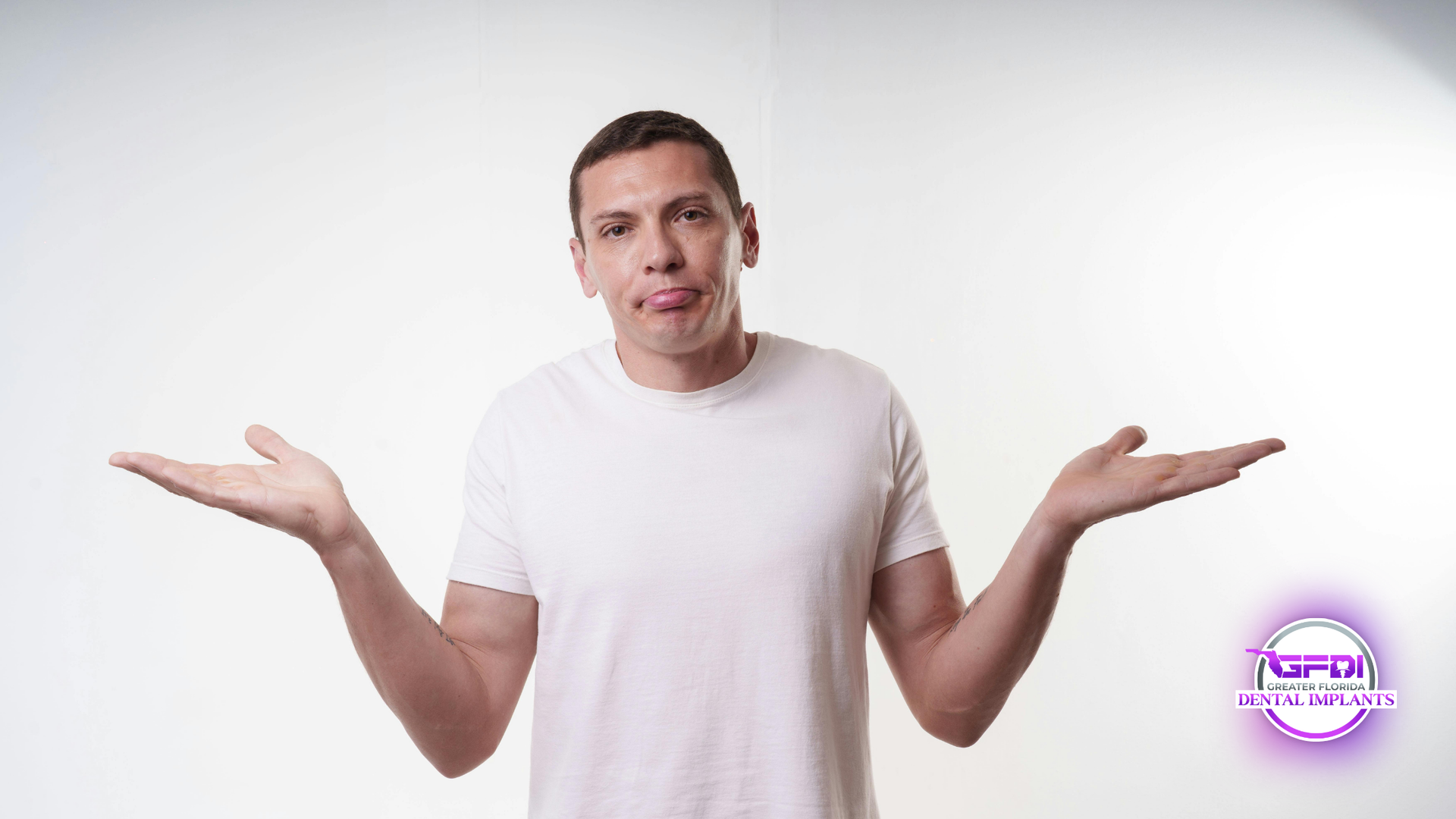 Man in white shirt shrugs with palms up, tongue out against a white background.
