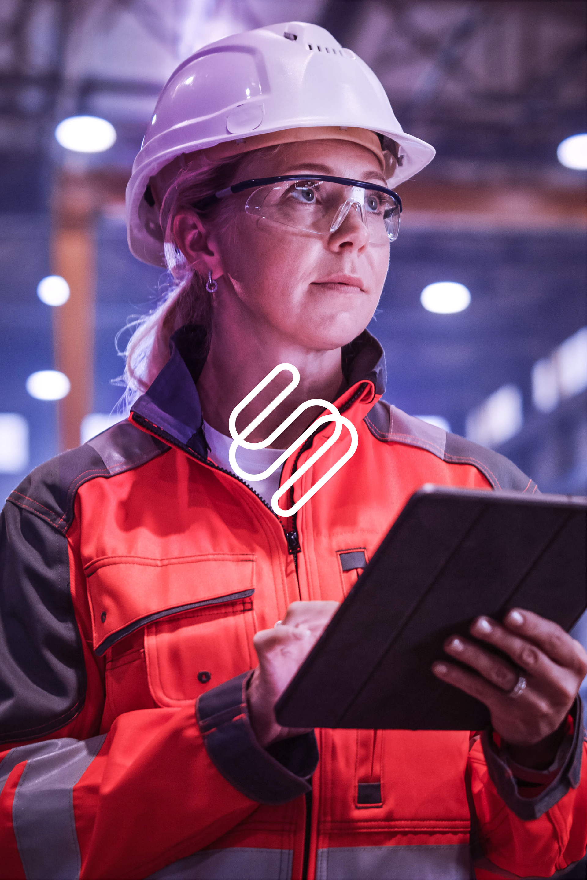 A woman wearing a hard hat and safety glasses is using a tablet computer.