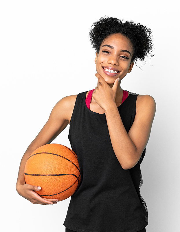 Woman in black athletic wear holding a basketball and smiling against a white background