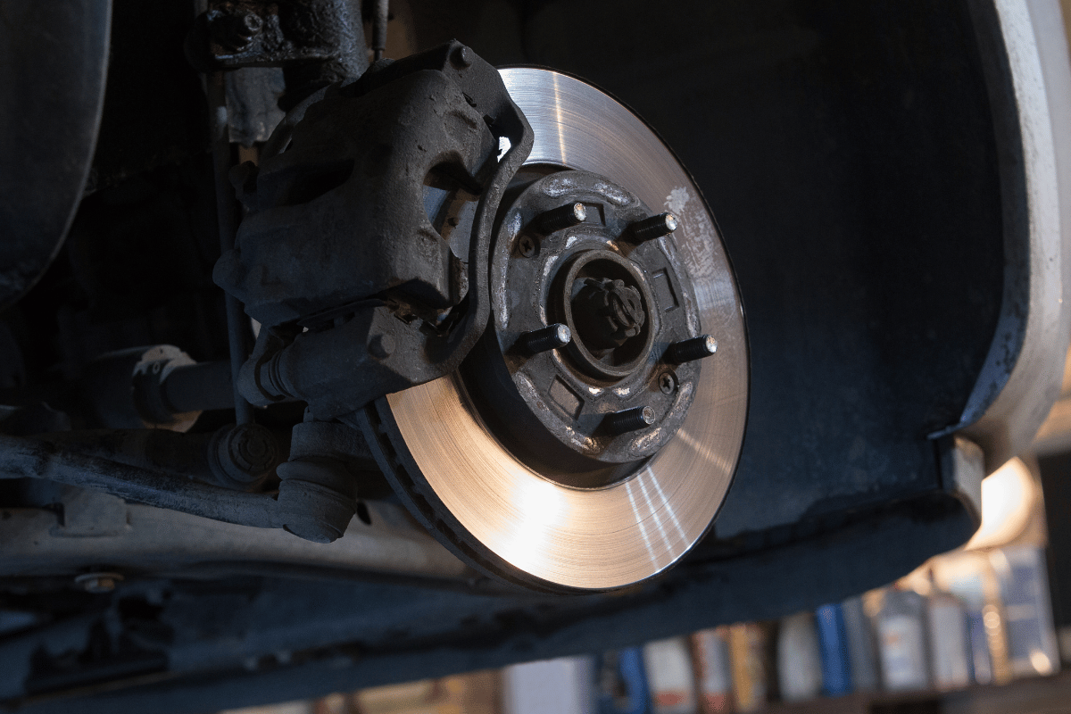 Close-up of a train wheel and brake disc on the track, with sparks or light reflecting on the metal surface