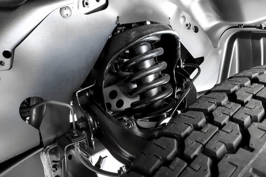 Close-up of a vehicle wheel well with suspension coil spring and rugged tire tread