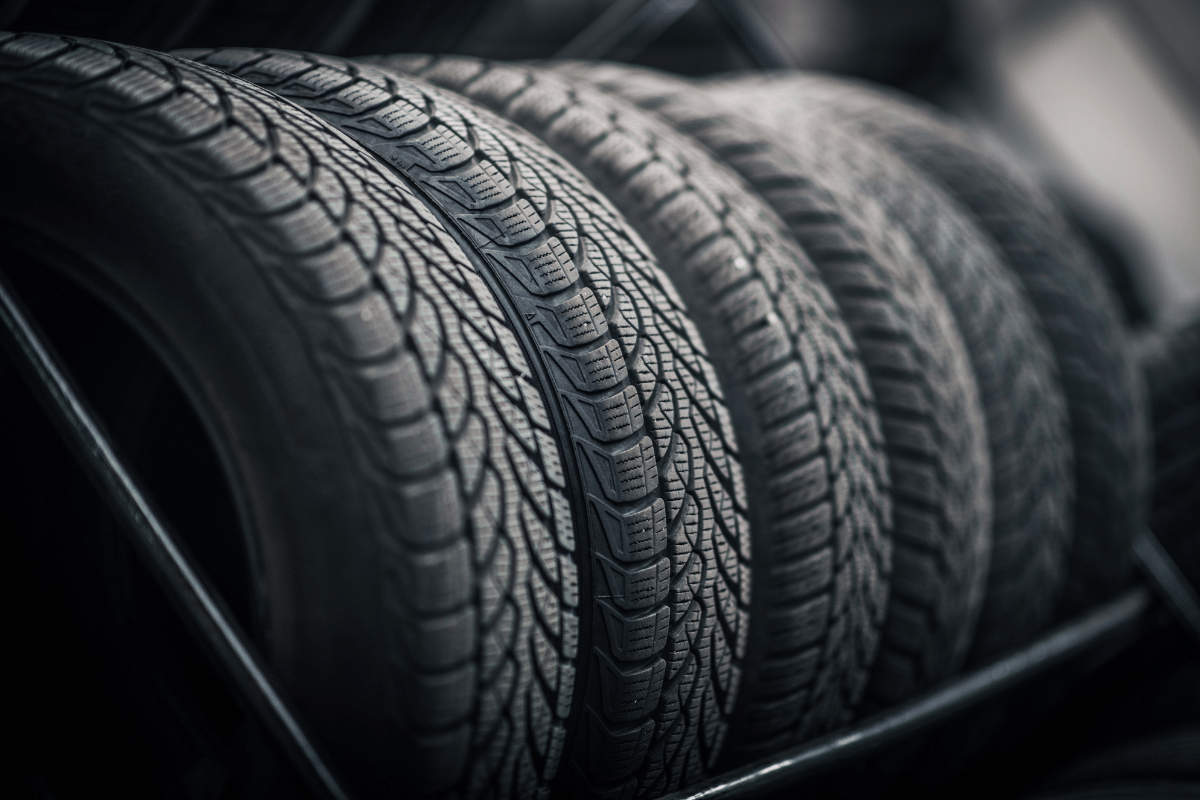 Stacked black car tires with detailed tread patterns in a dark garage setting