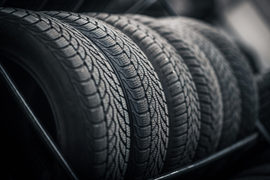 Stacked black car tires with visible tread patterns in a dim setting