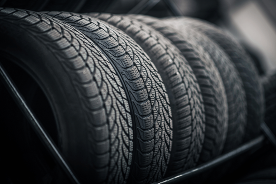 Stacked black car tires with visible tread patterns in a dim setting