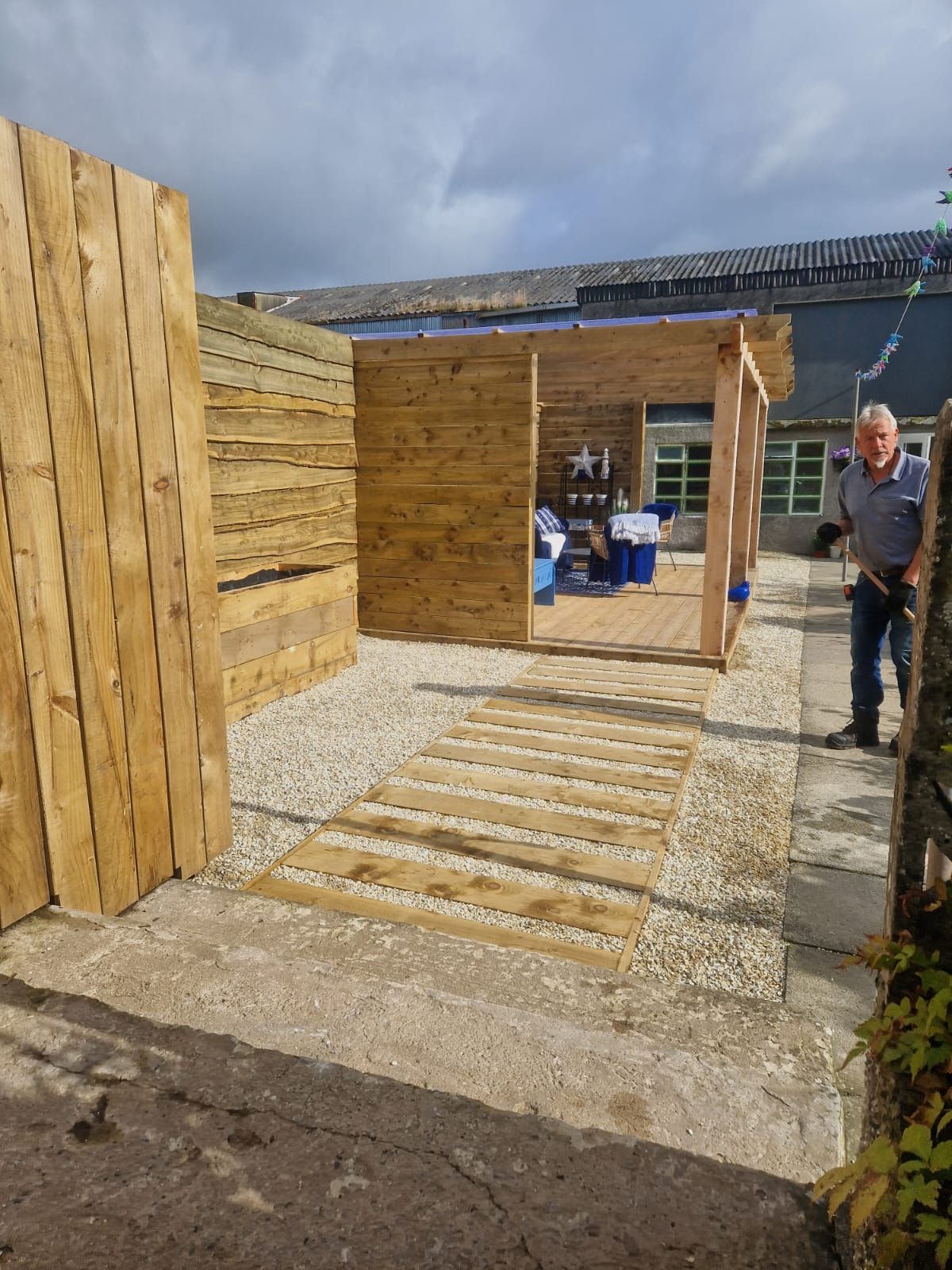 A man is standing in front of a wooden structure