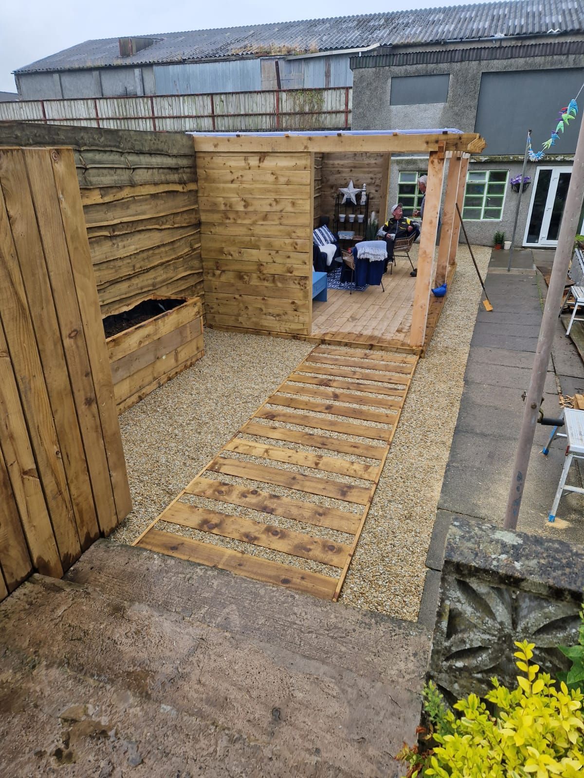 A wooden shed with a table and chairs in a backyard.