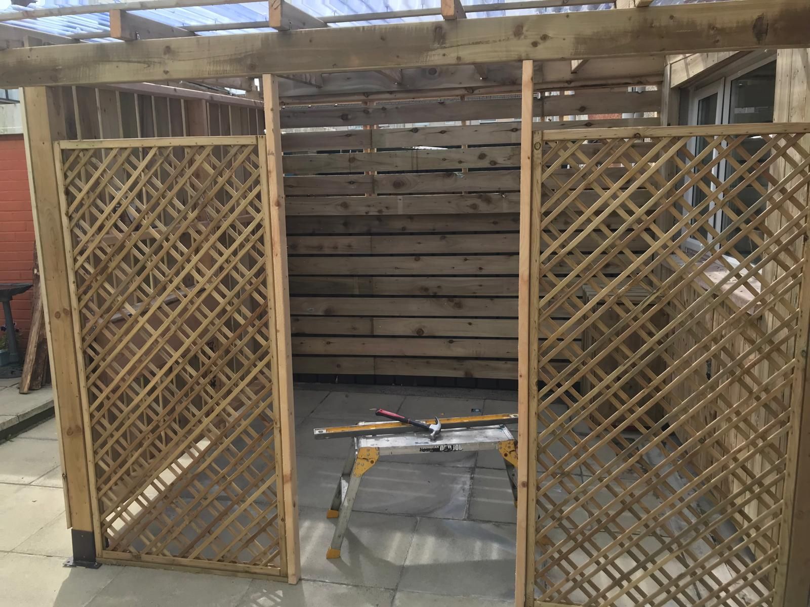 A wooden structure with a lattice on the side is being built.