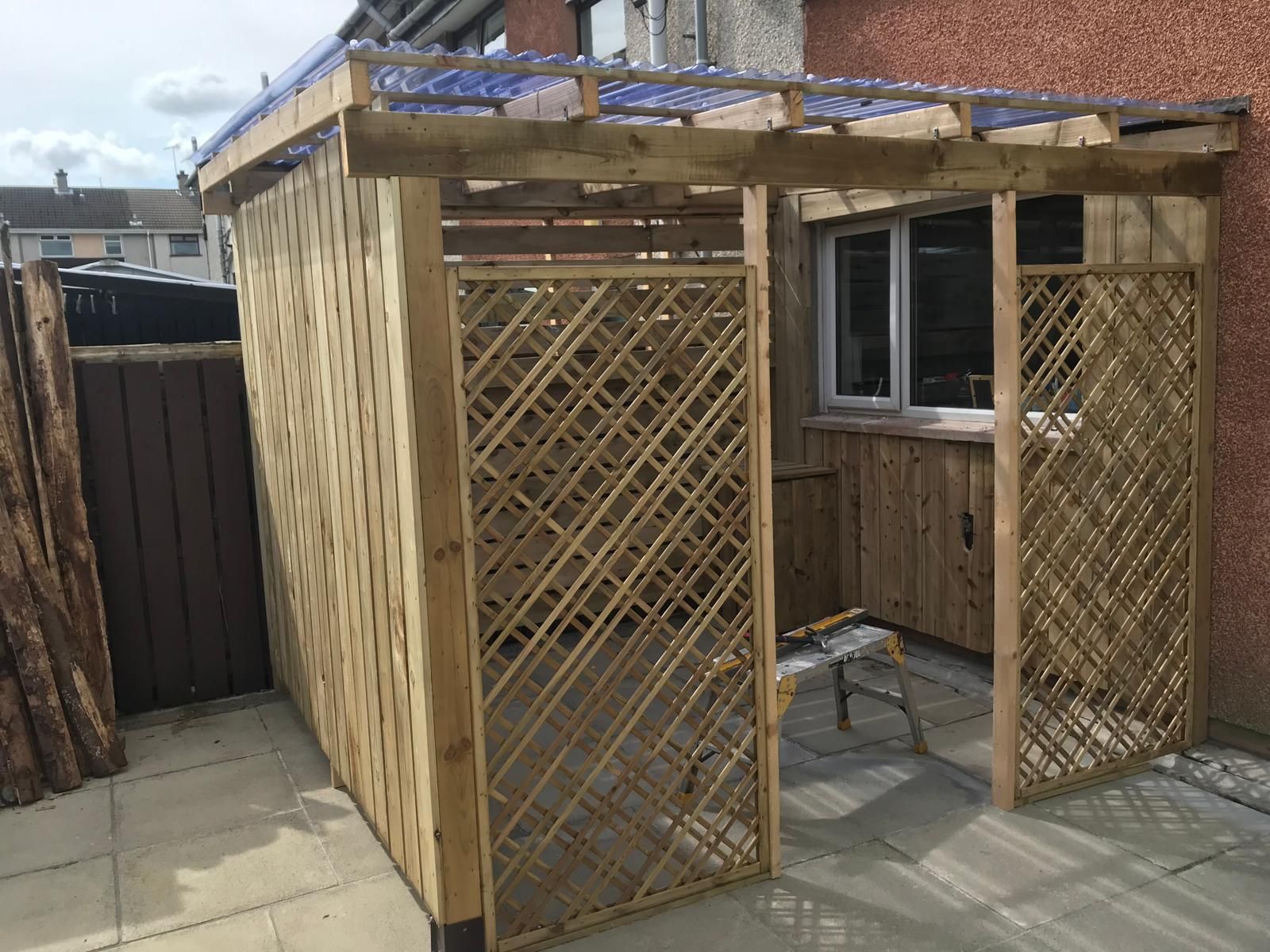 A wooden structure is being built on a patio in front of a building.