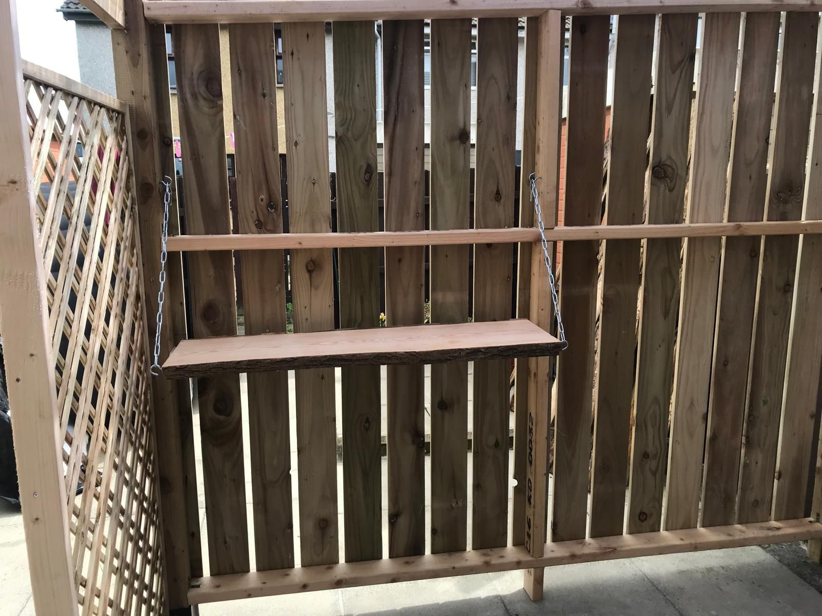 A wooden fence with a shelf attached to it