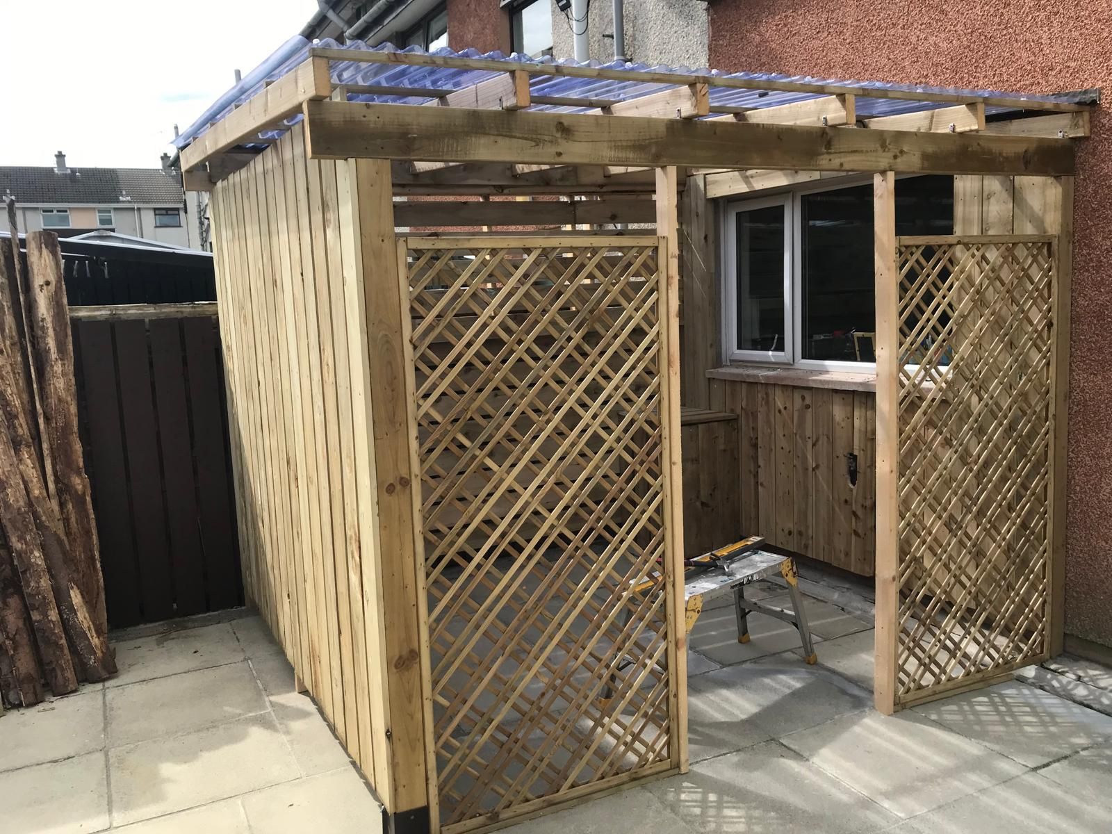 A wooden structure is being built in the backyard of a house.