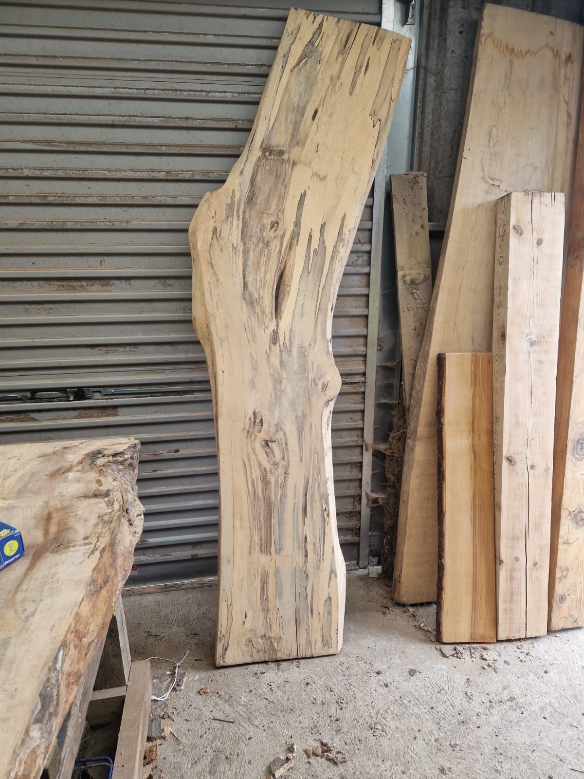 A large piece of wood is sitting on the ground in front of a garage door.