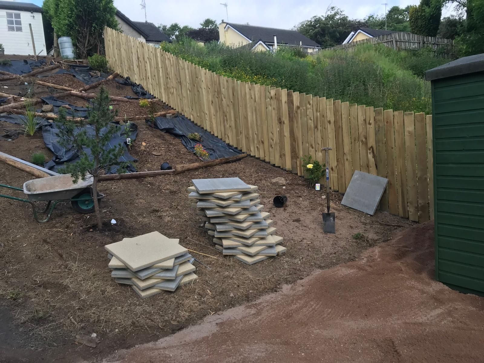 A wooden fence is being built in the backyard of a house.