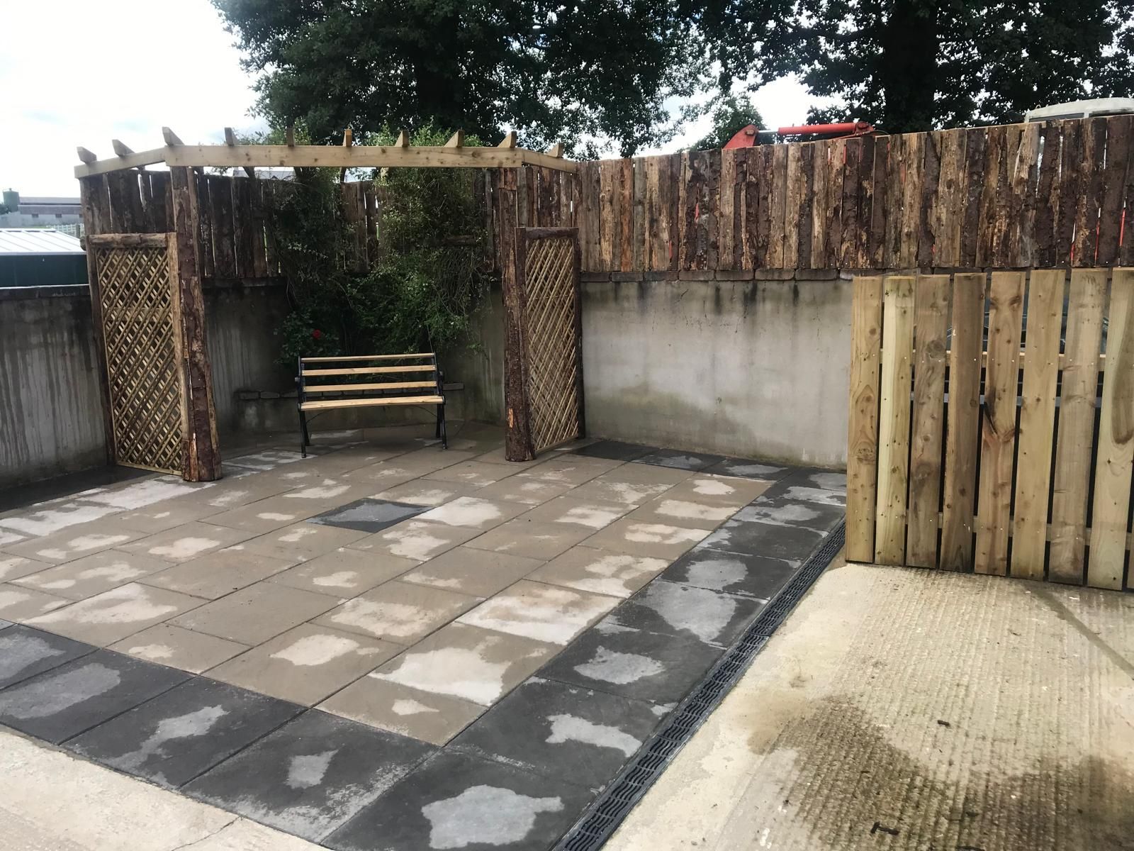 A patio with a wooden bench and a wooden fence
