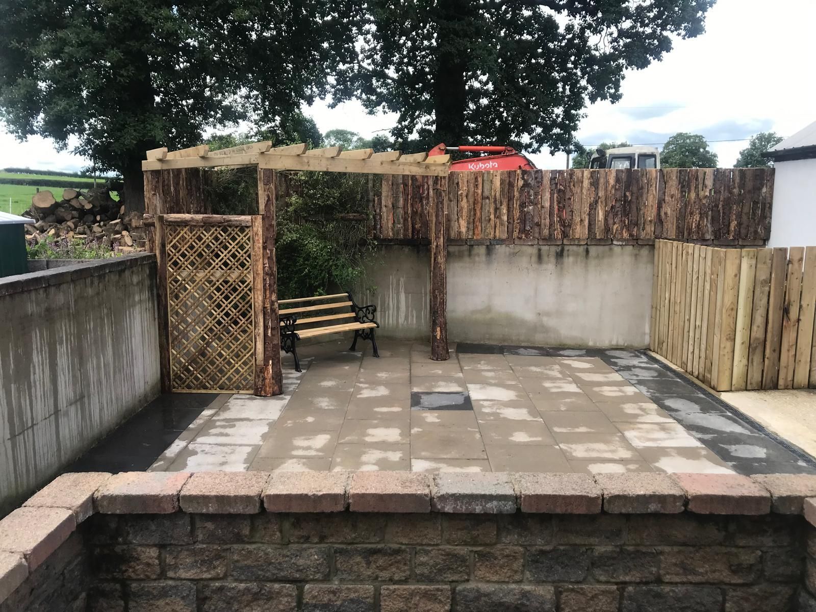 A patio with a wooden pergola and a bench