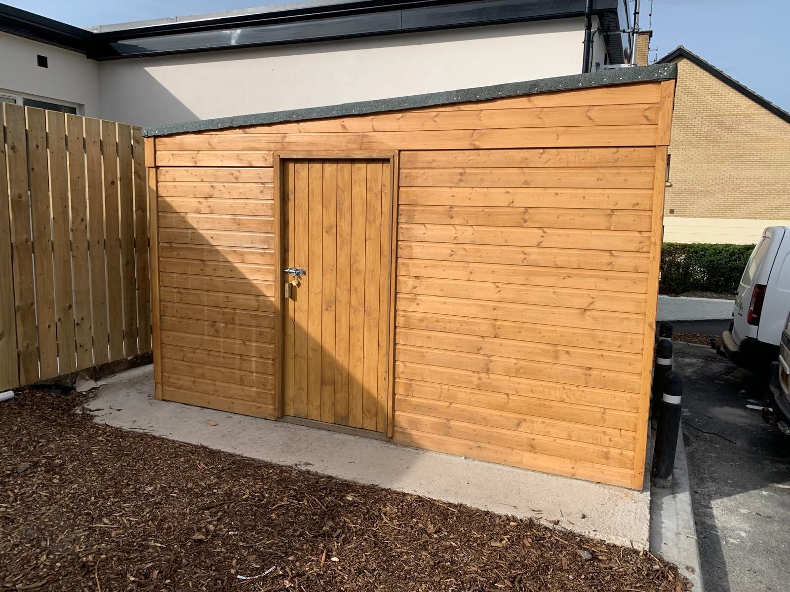 A wooden shed is sitting in the backyard of a house.