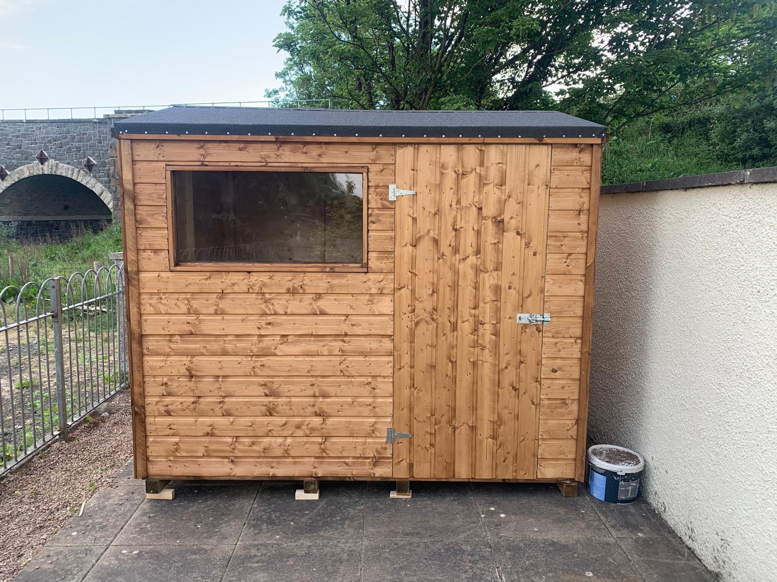 A small wooden shed with a window on the side of it