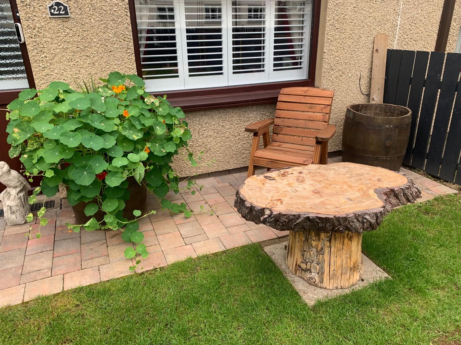 A wooden table and chair made out of a tree stump in front of a house.