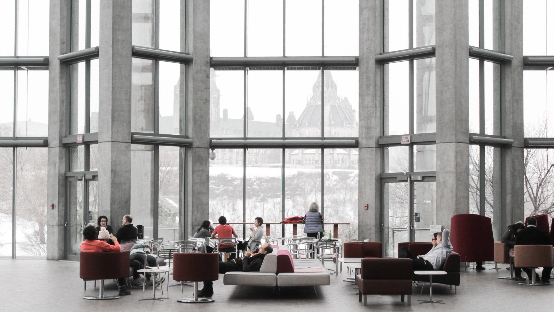 a group of people are sitting in a large room with a lot of windows .