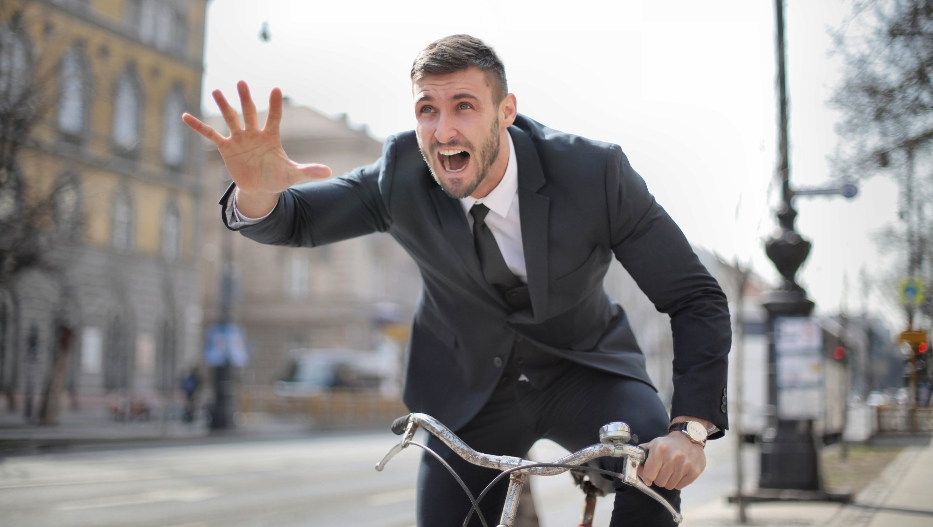 a man in a suit and tie is riding a bicycle down a street .