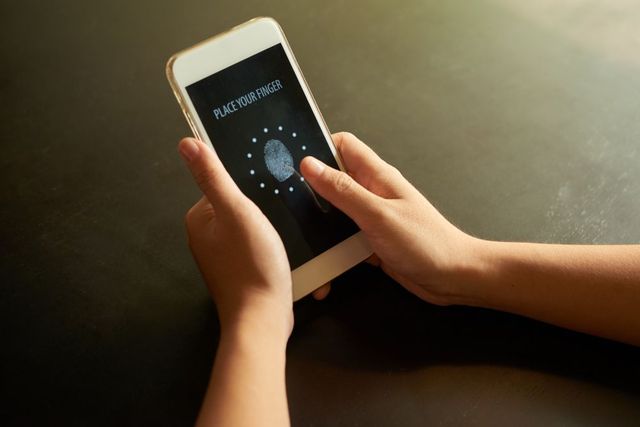 A person is holding a cell phone with a fingerprint on the screen.